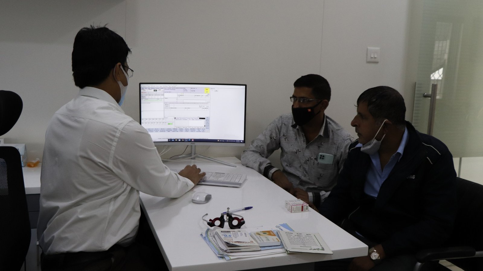 A counselling session at Aastha Eye Care — a staff member reviewing findings with patients.